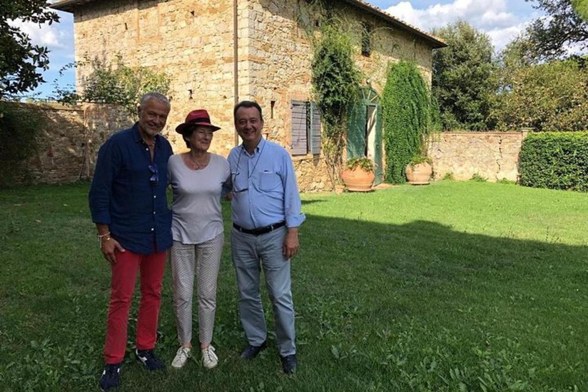 un grup de trei persoane care stau în fața unei case