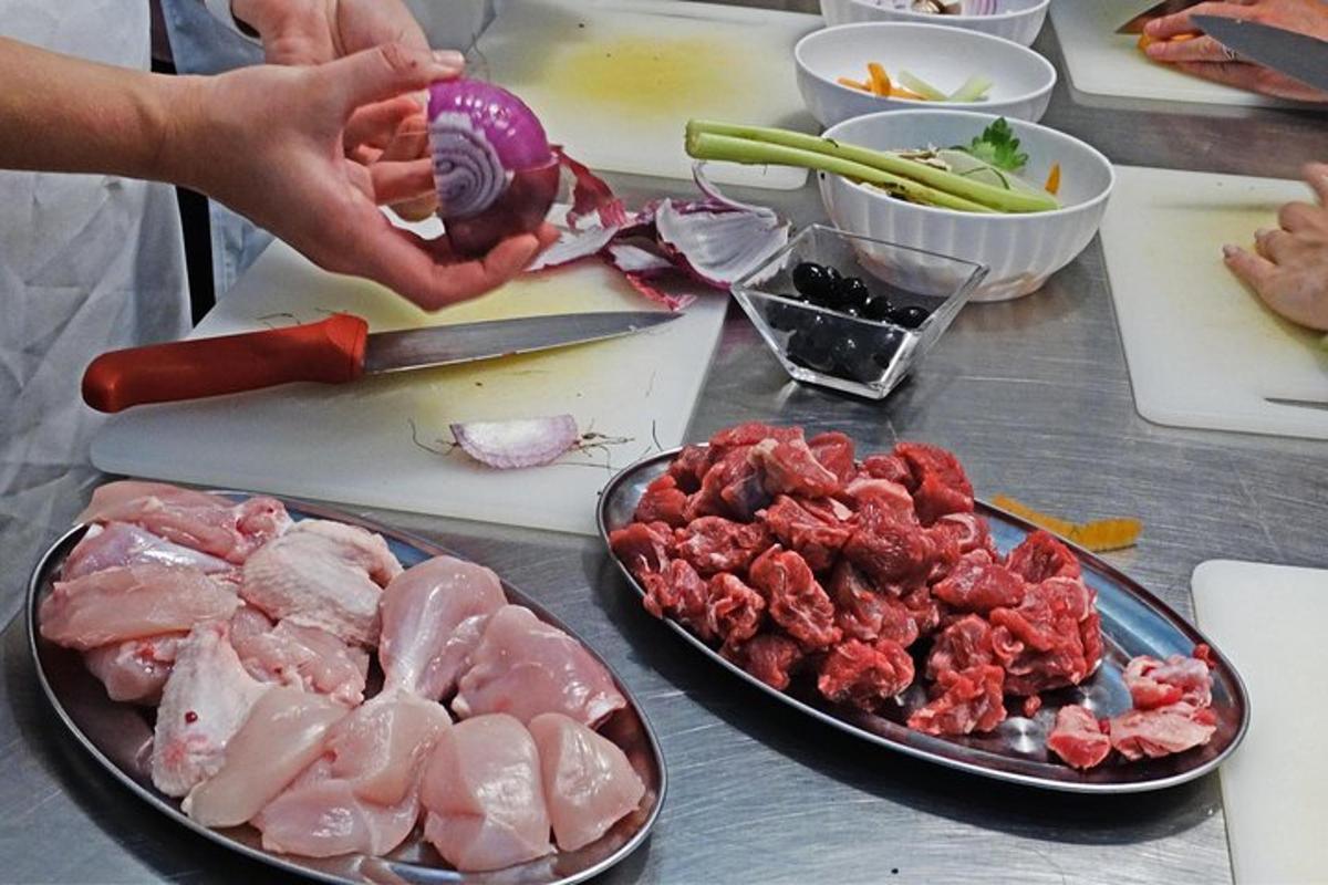 Una mesa con carne y verduras y una persona cocinando
