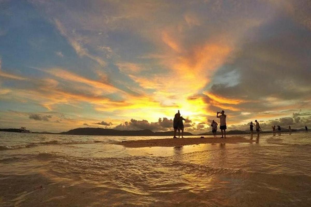 a group of people standing on the beach at sunset