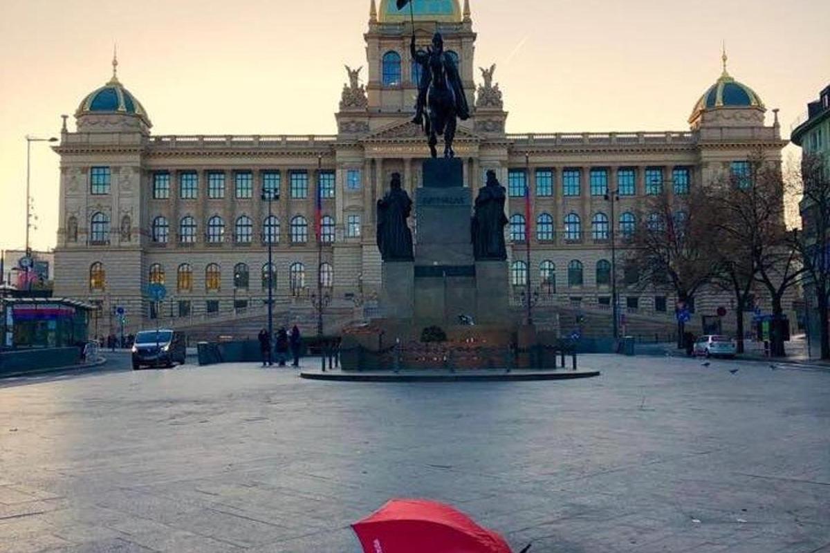 osoba s červeným dáždnikom pred veľkou budovou