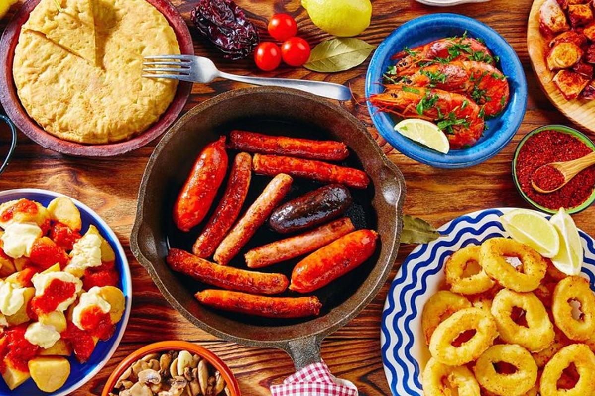 una taula amb una paella plena de salsitxes i altres aliments