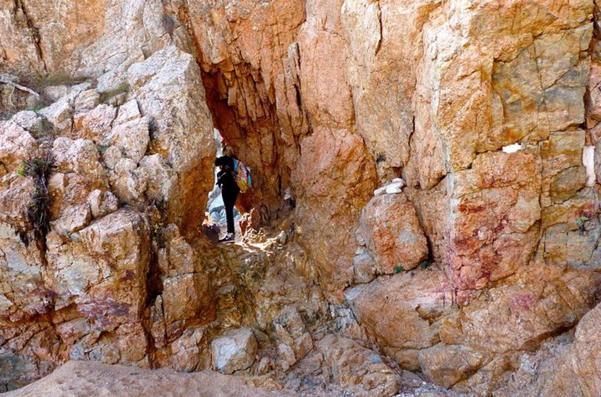a person is walking through a cave in a rock wall