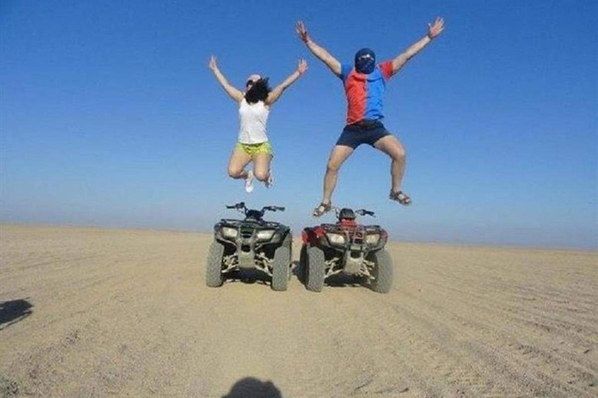 Dos personas saltando en el aire junto a un quad en el desierto