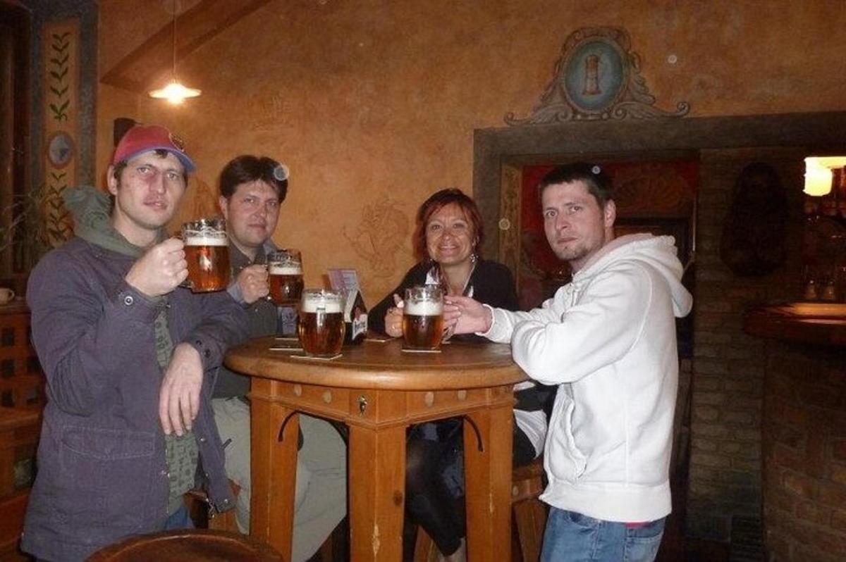 skupina mužů sedících kolem stolu a popíjejících pivo