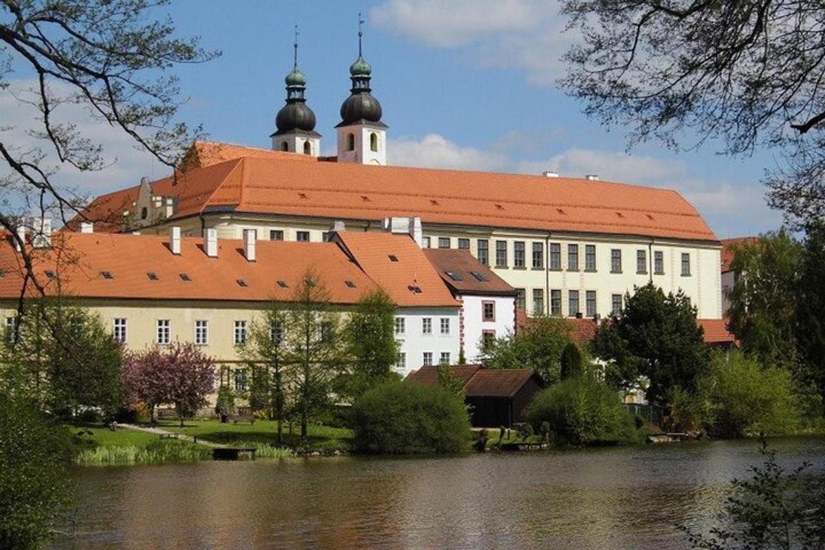 Velká bílá budova s červenou střechou vedle jezera