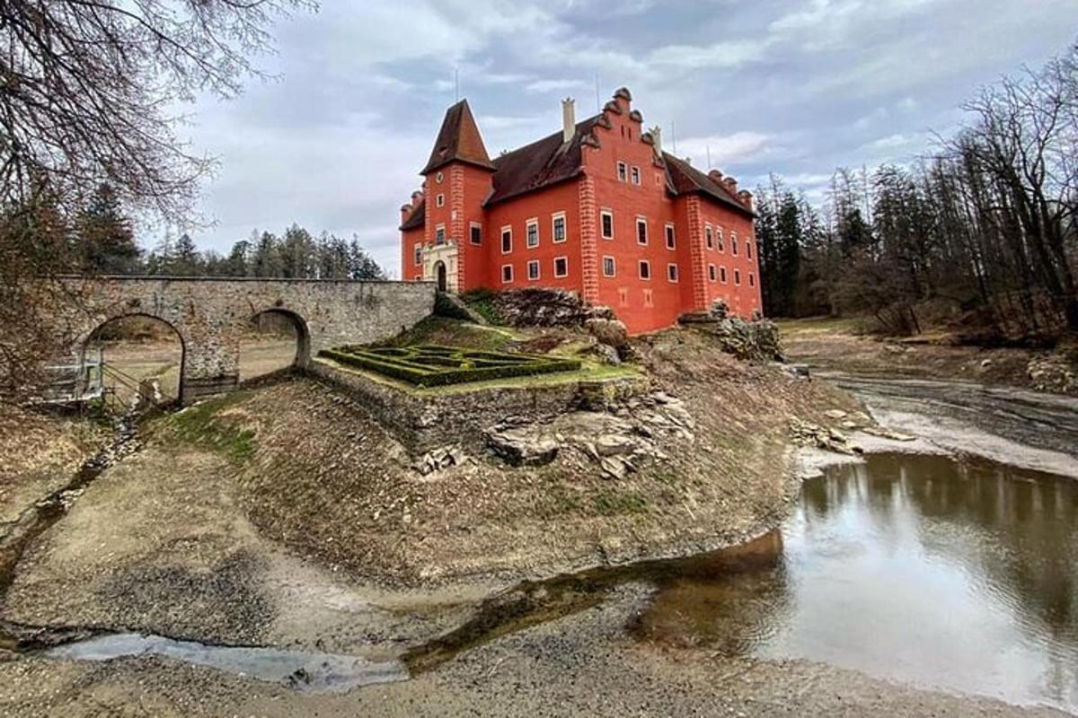 un grande edificio rosso su una collina con un ponte