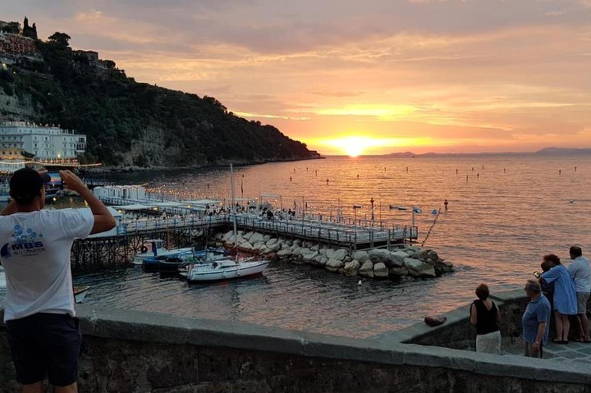 Un hombre tomando una fotografía de la puesta de sol sobre el agua.
