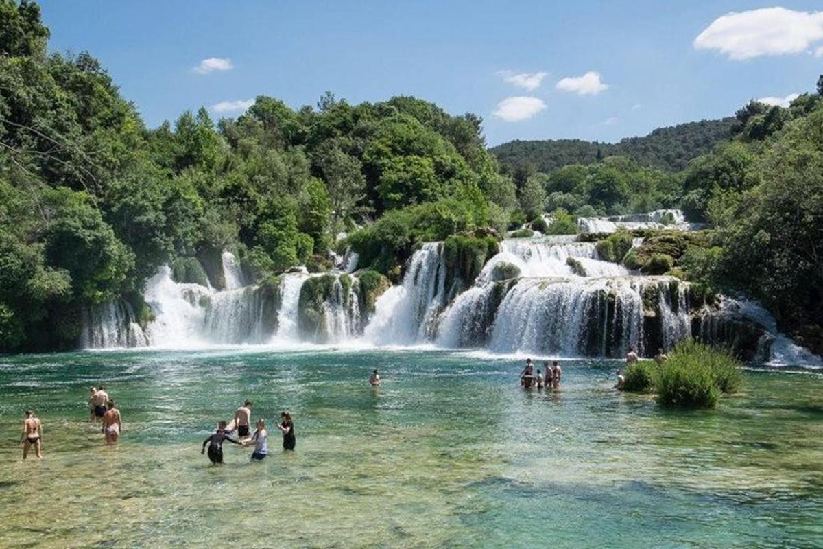 persone che nuotano nell'acqua di fronte alla cascata