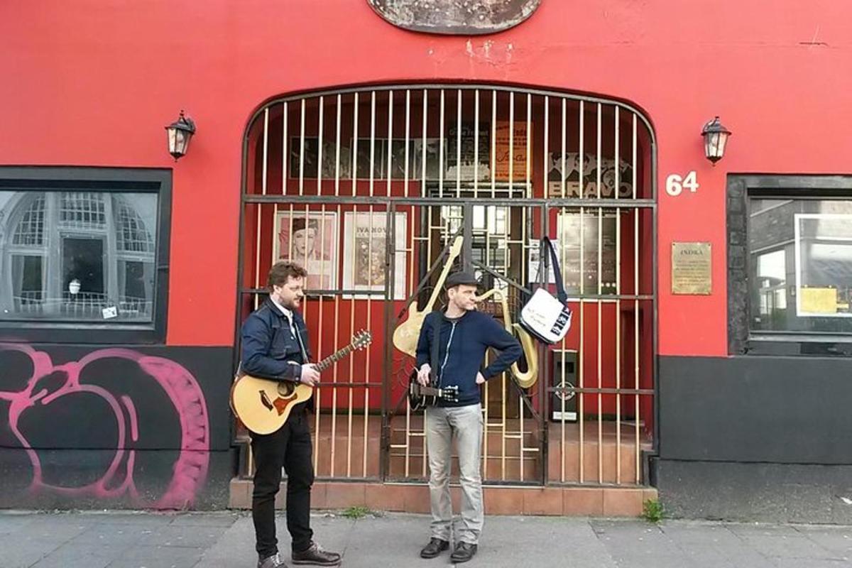 dois homens parados na calçada tocando violão