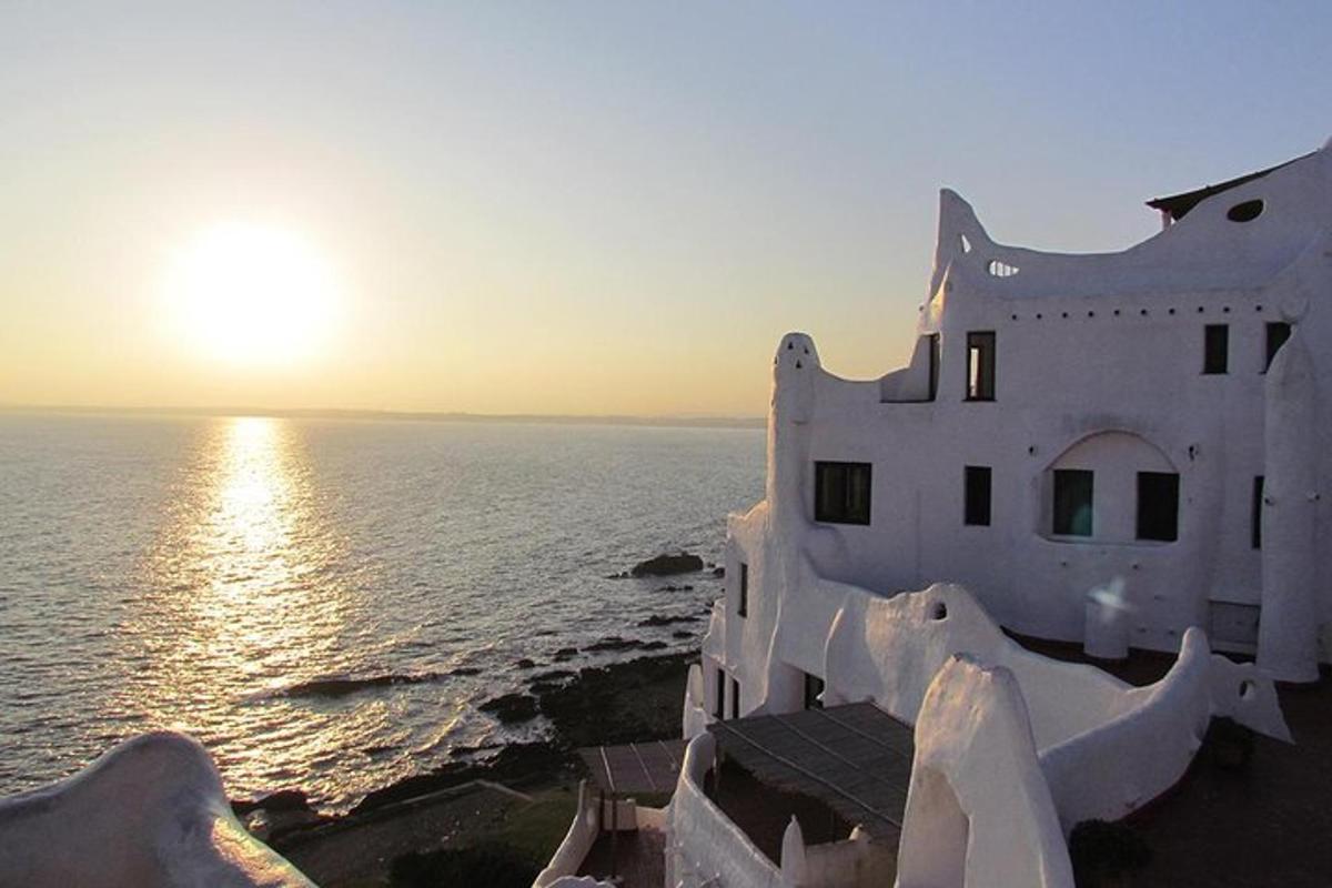 a building on the edge of the ocean at sunset