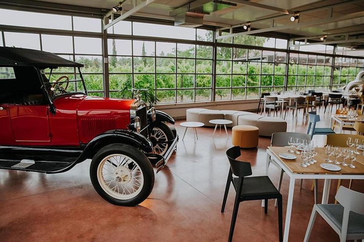 um velho carro vermelho estacionado em uma sala com mesas e cadeiras