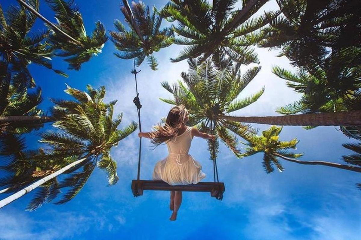 una donna è seduta su un'altalena tra le palme