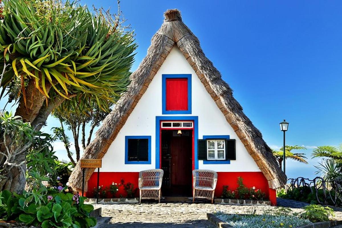 una petita casa amb teulada de palla i cadires