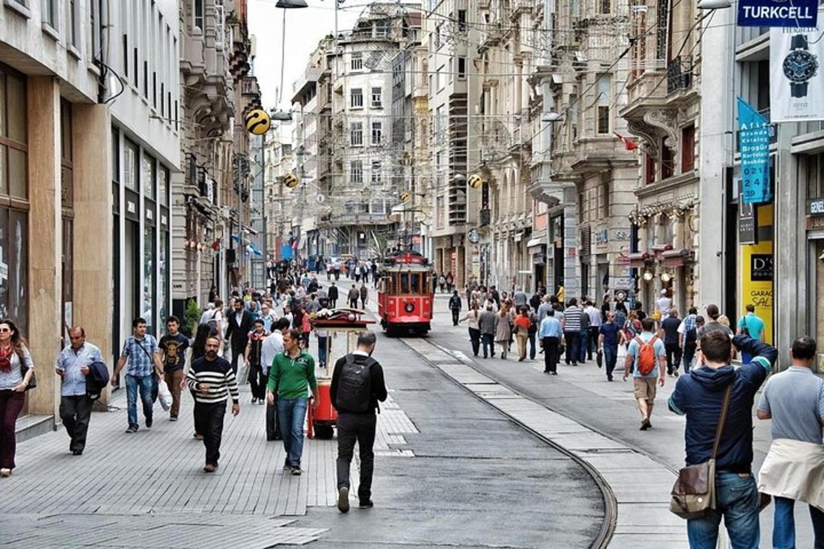 a busy city street with people walking and a red trolley