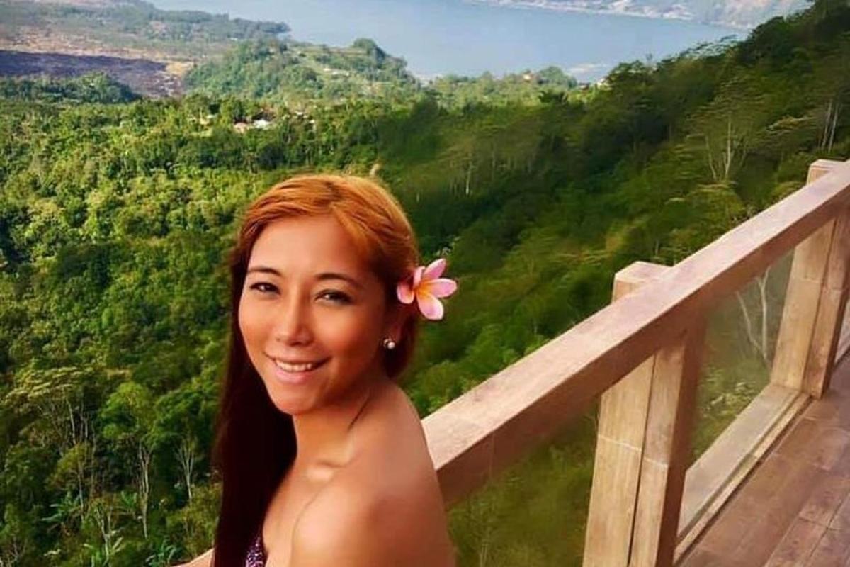una dona amb una flor als cabells dreta a un balcó
