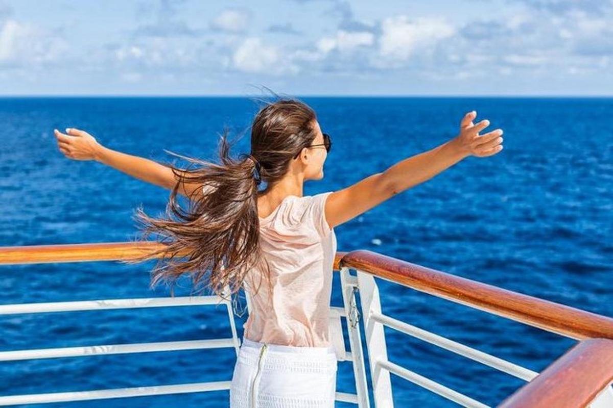 một người phụ nữ đứng trên một con tàu du lịch với hai tay dang rộng