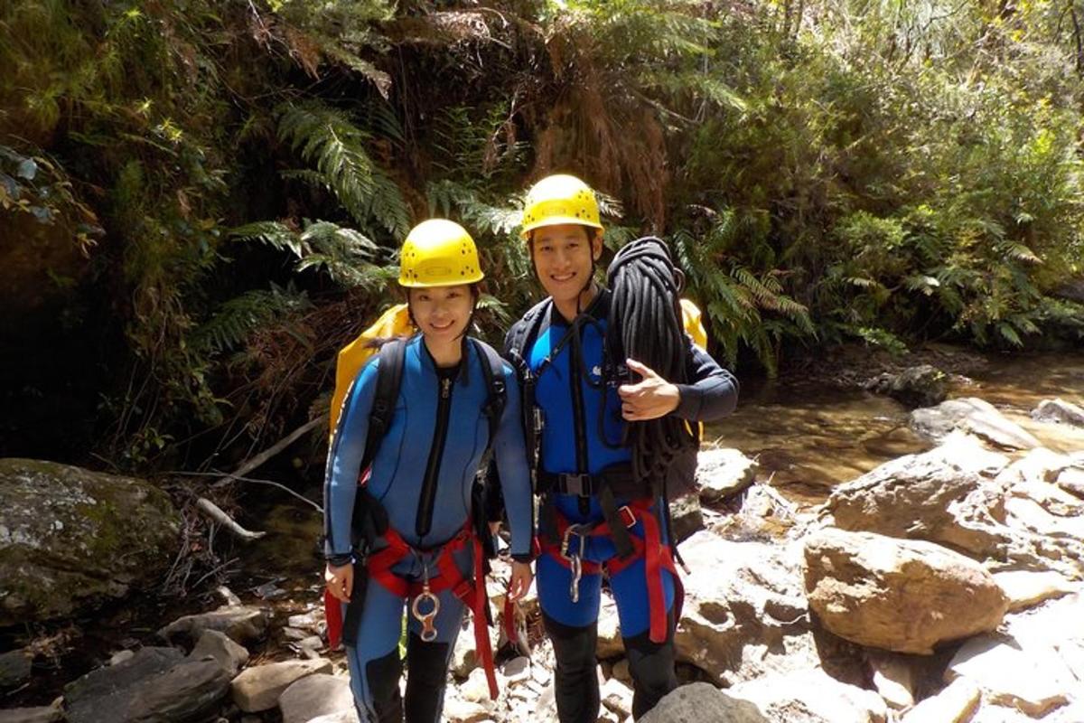 two boys wearing life jackets and helmets standing in a river