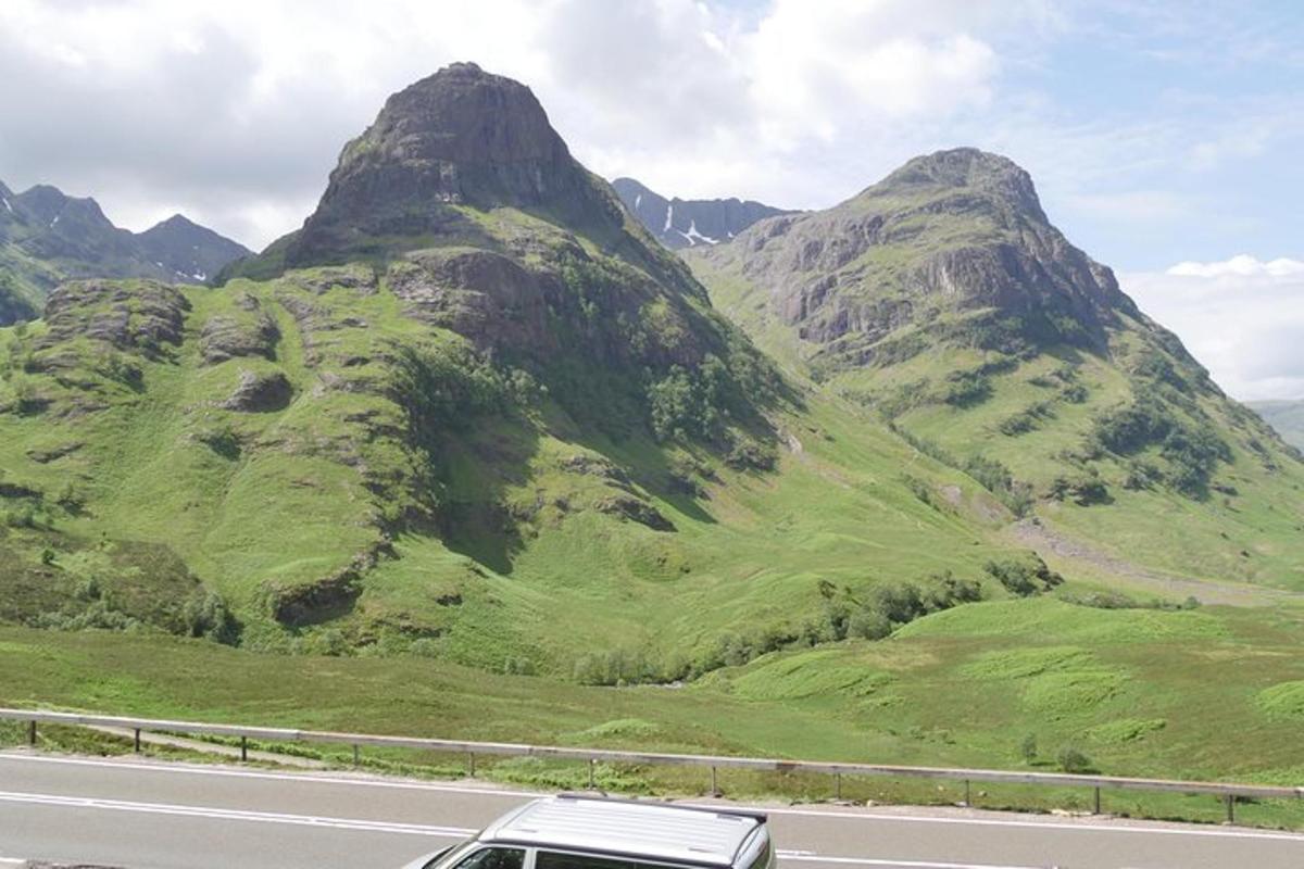 a car driving on a road in front of a mountain