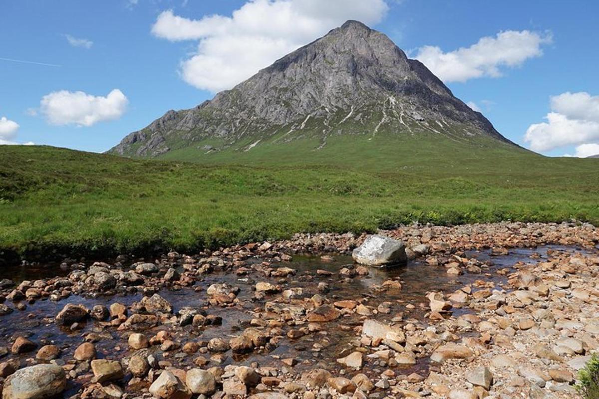 uma montanha ao longe com um rio e pedras