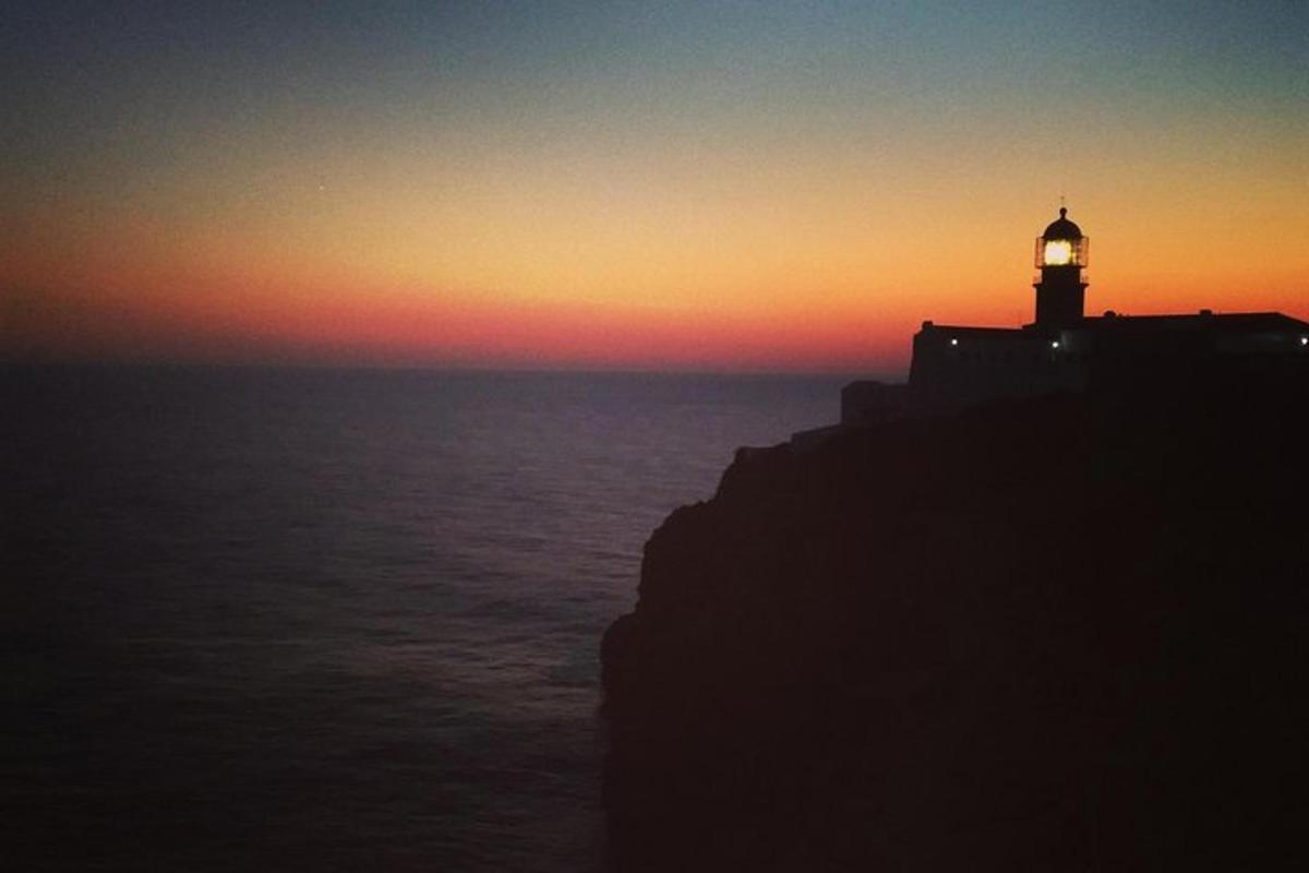 a lighthouse sitting on top of the ocean at sunset