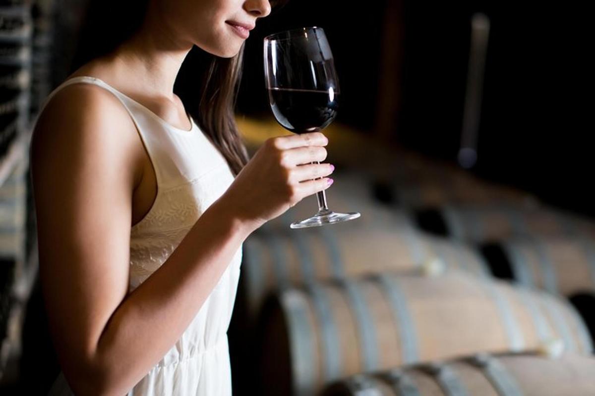 una donna in abito bianco che tiene in mano un bicchiere di vino