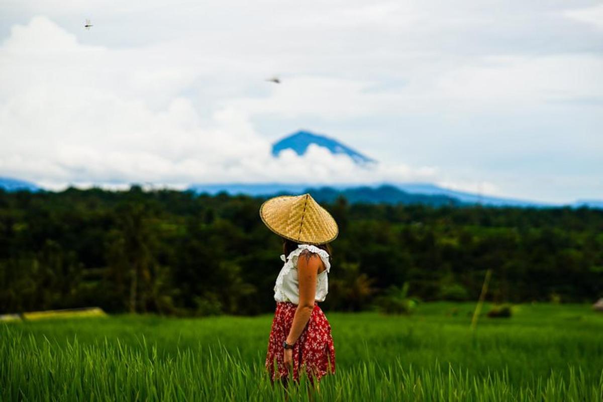 uma mulher em um campo com um chapéu empinando uma pipa
