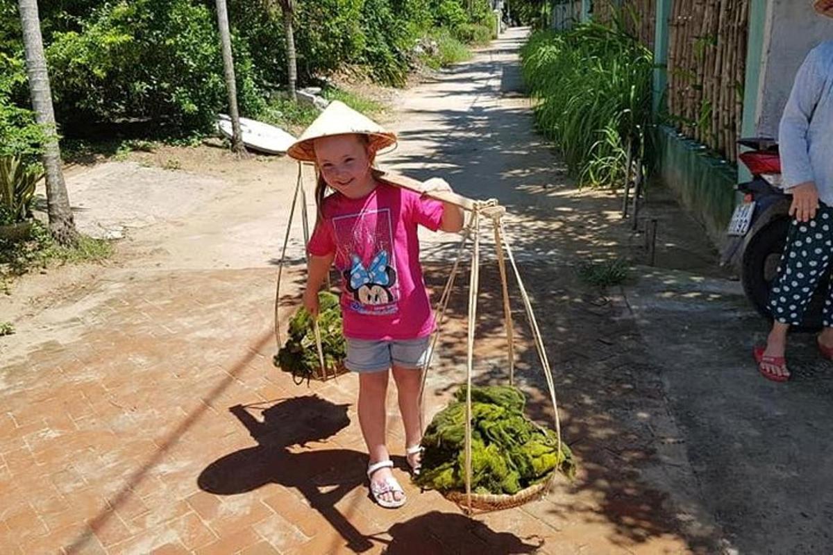 Una niña con un sombrero de paja sosteniendo una canasta de verduras