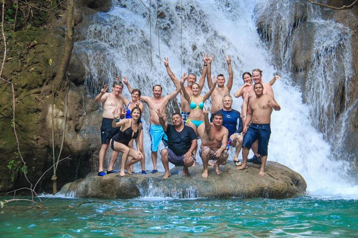 a group of people standing on a rock in front of a waterfall