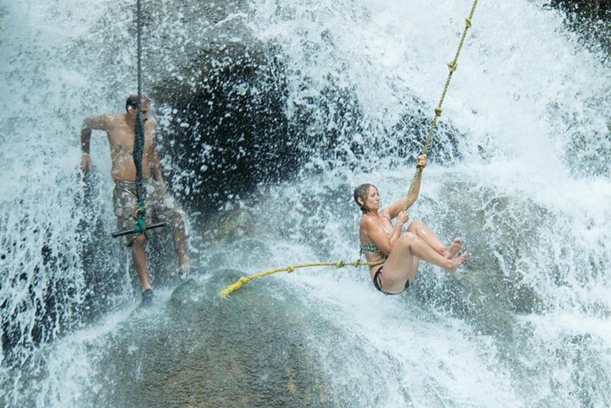 two people are on a rope in a waterfall