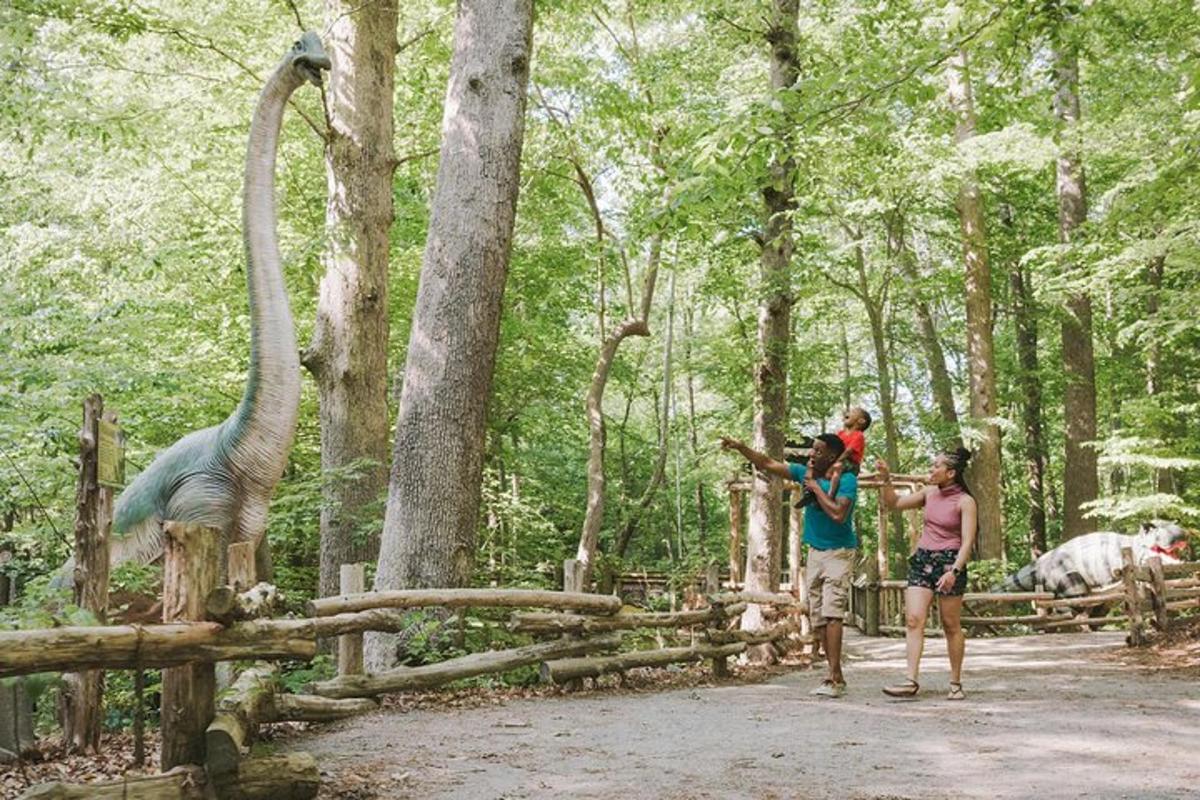 a group of people looking at a giraffe and a dinosaur