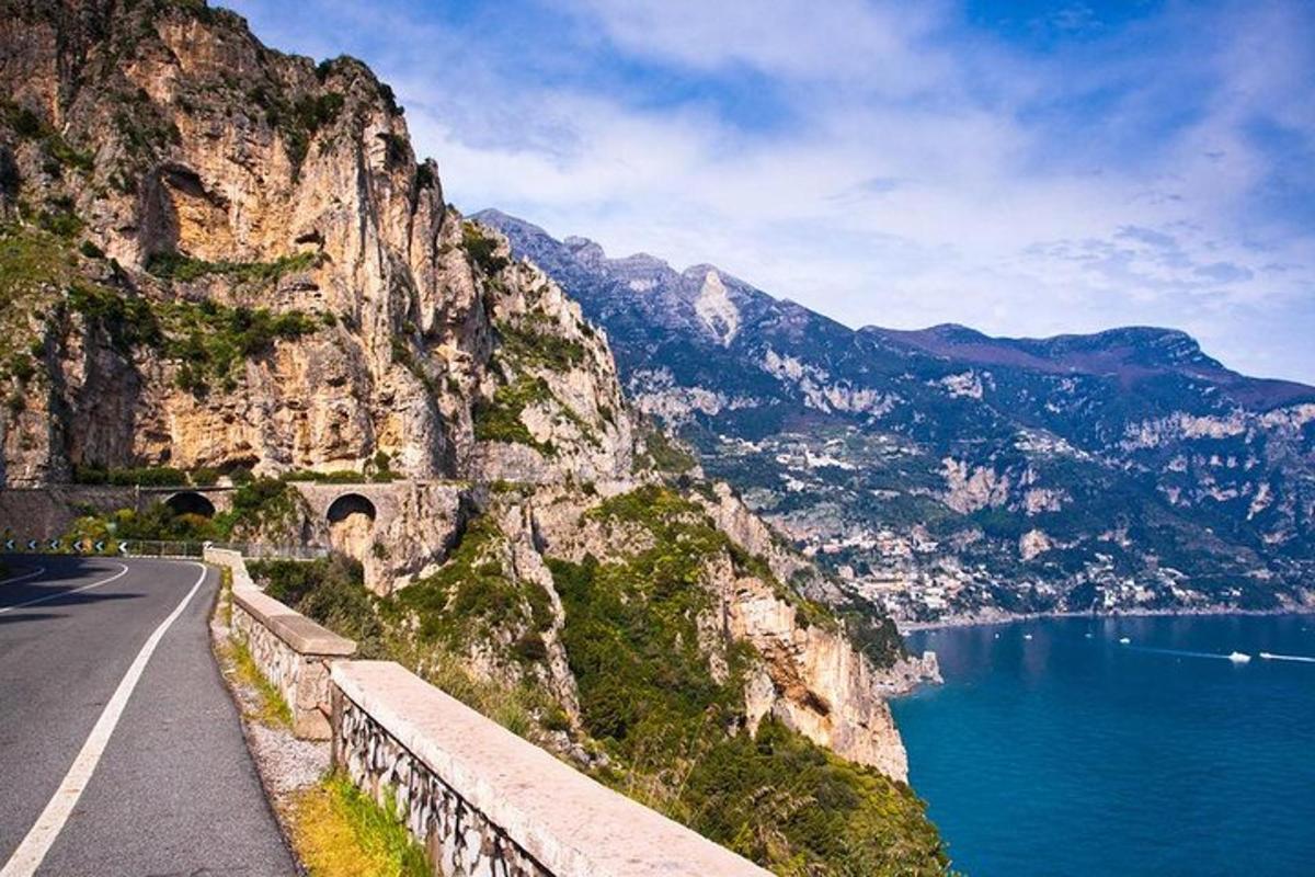 un camino en la ladera de una montaña al lado de un cuerpo de agua