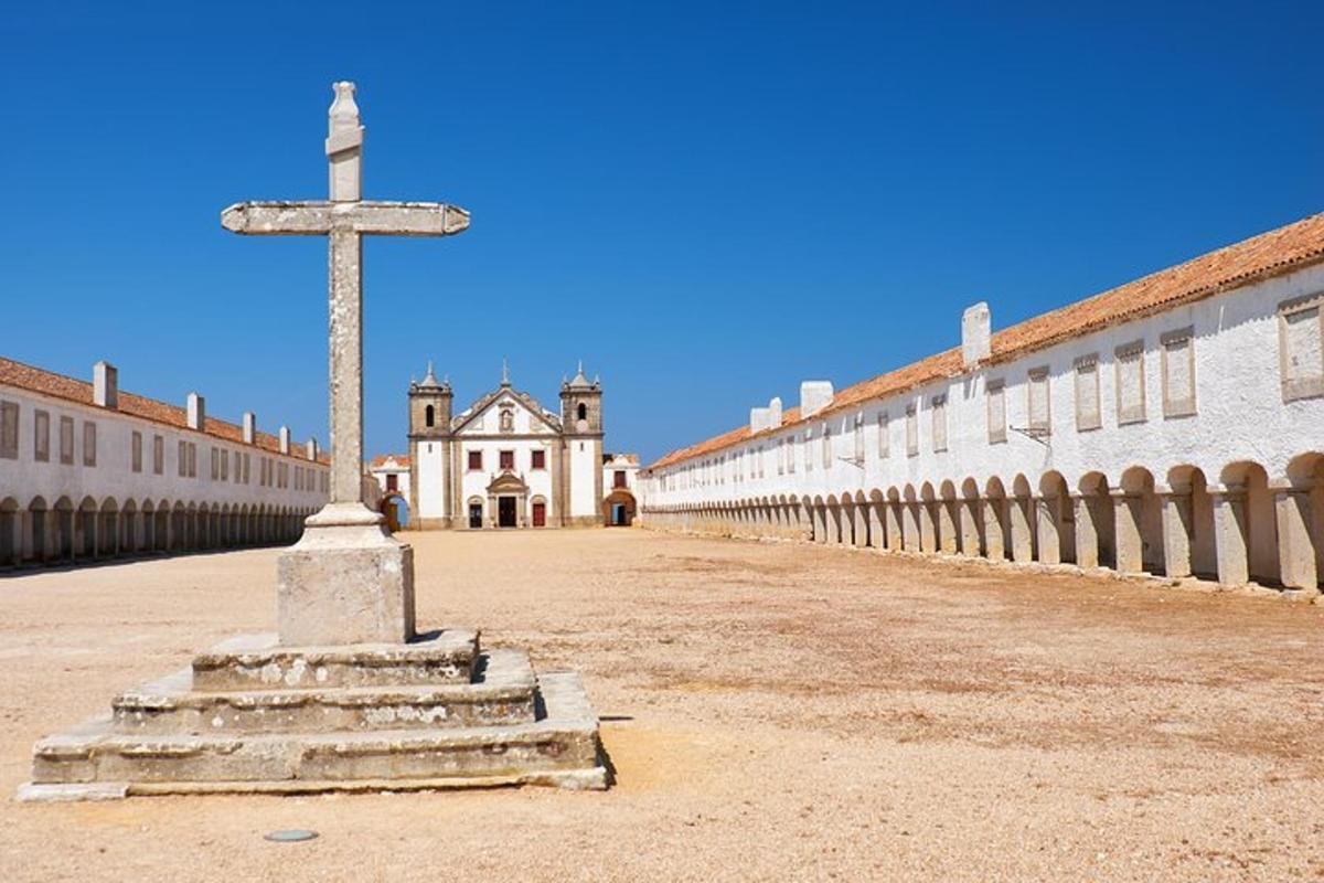 uma cruz no meio de um pátio com um edifício