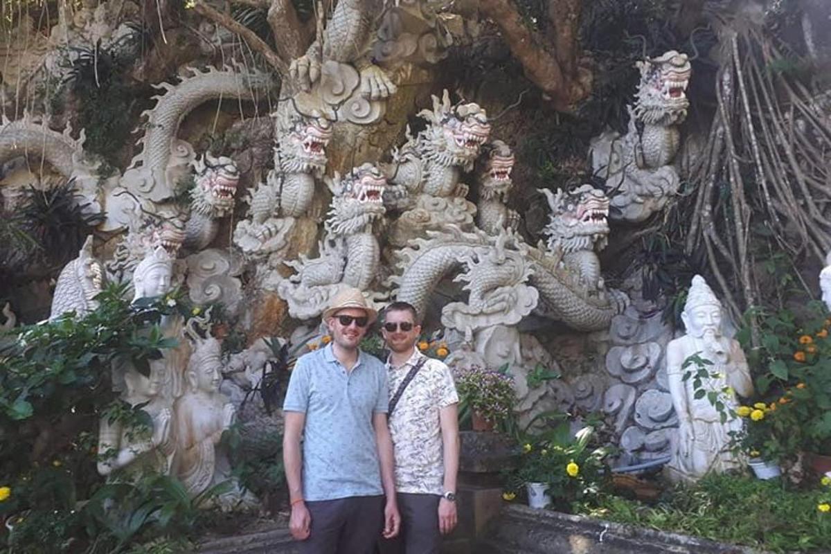 Dos personas de pie frente a una pared de estatuas.