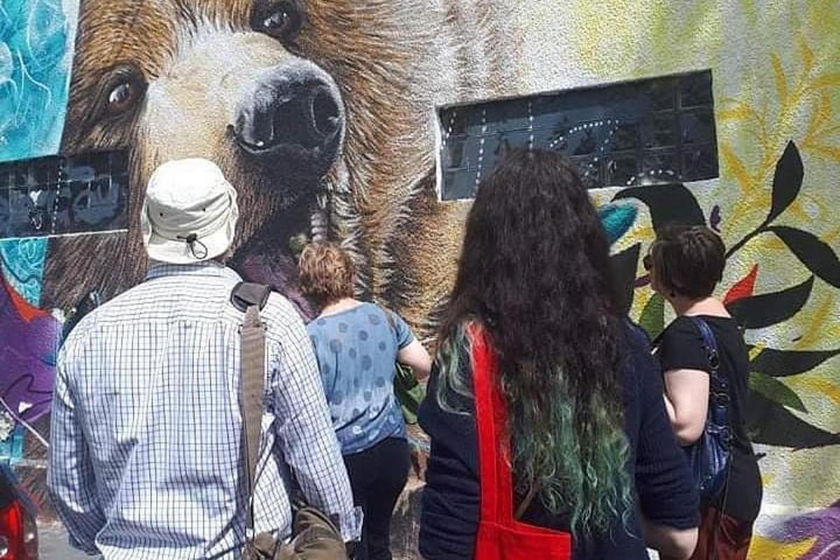 people standing in front of a mural of a brown bear