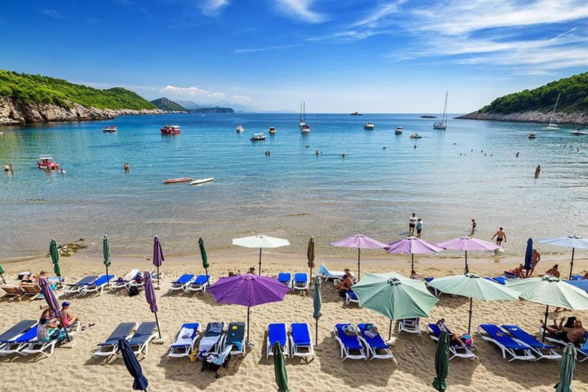 pantai dengan kerusi dan payung dan orang di dalam air