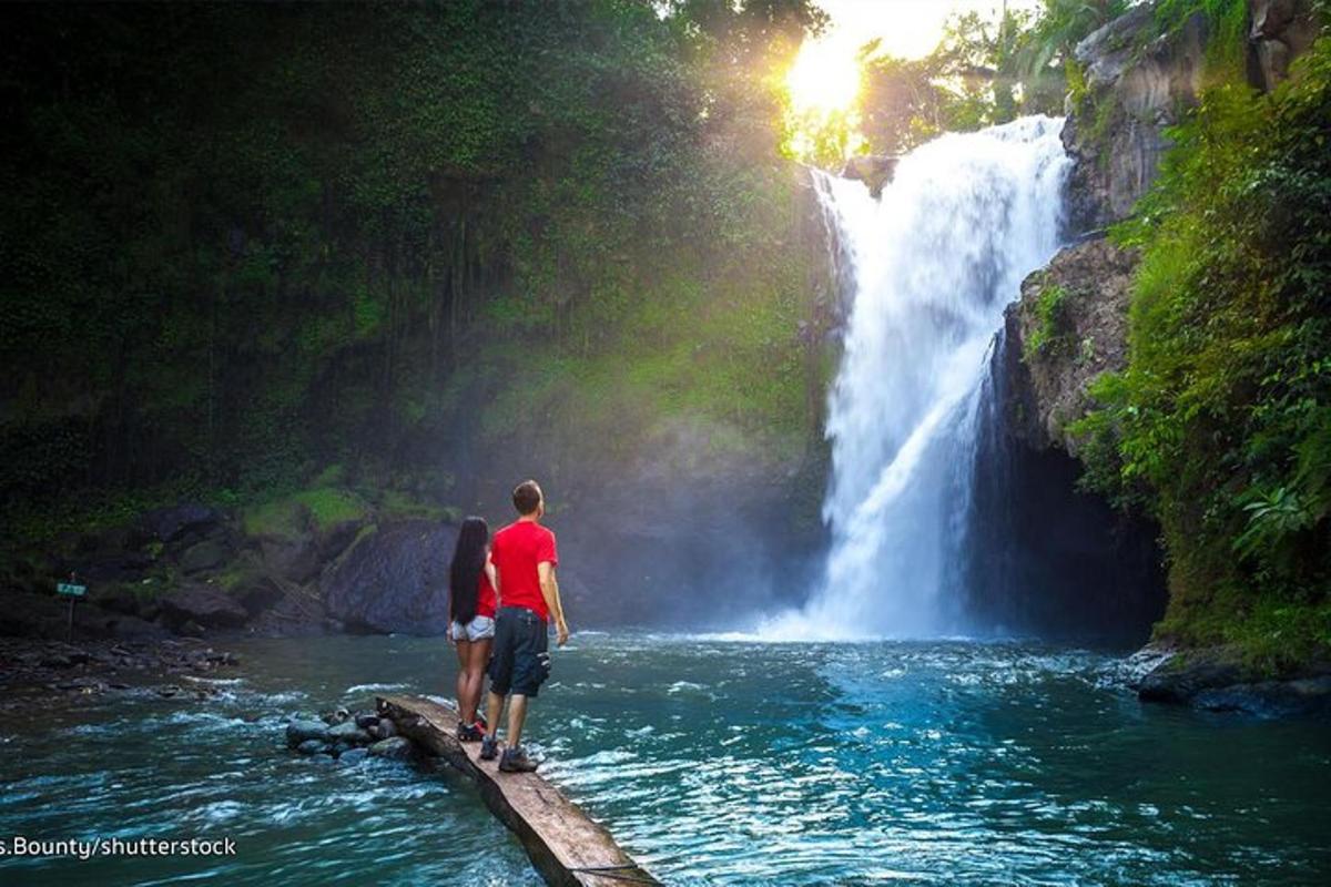 Maður og kona standa á brú fyrir framan foss