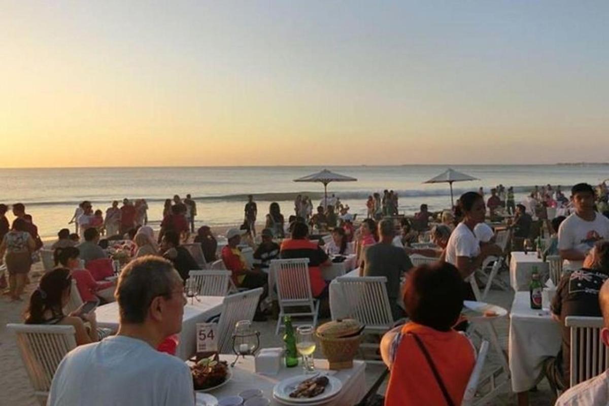 un gruppo di persone sedute ai tavoli sulla spiaggia