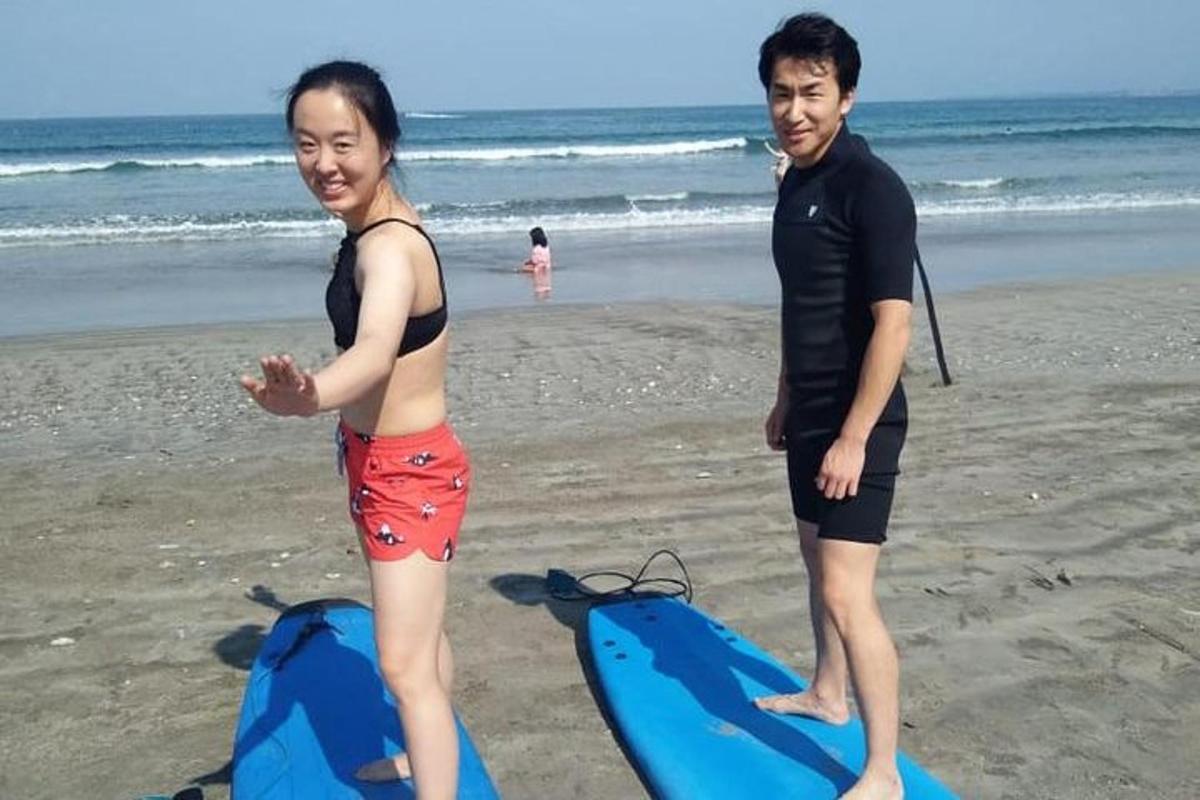 mężczyzna i kobieta stojący na plaży z deską surfingową