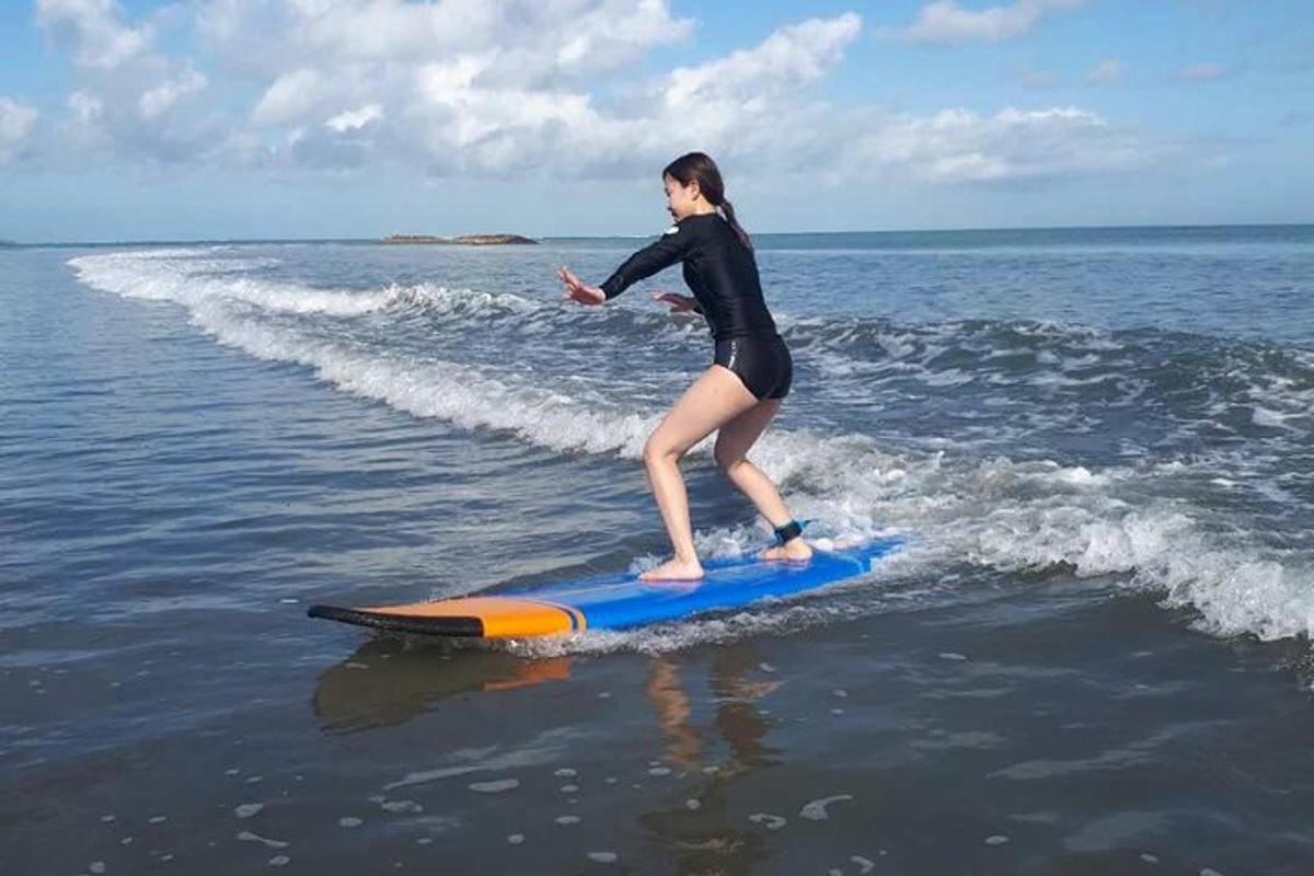 žena stojící na surfovém prkně v oceánu