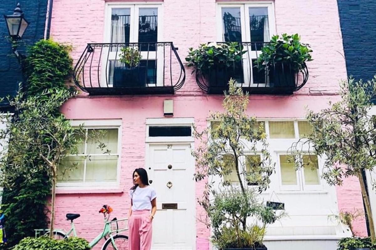 a woman standing in front of a pink house