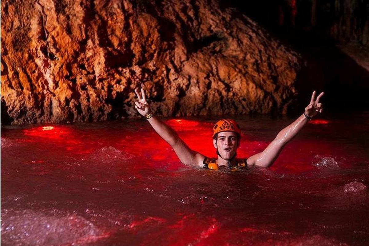 un uomo in acqua con le braccia alzate in una grotta