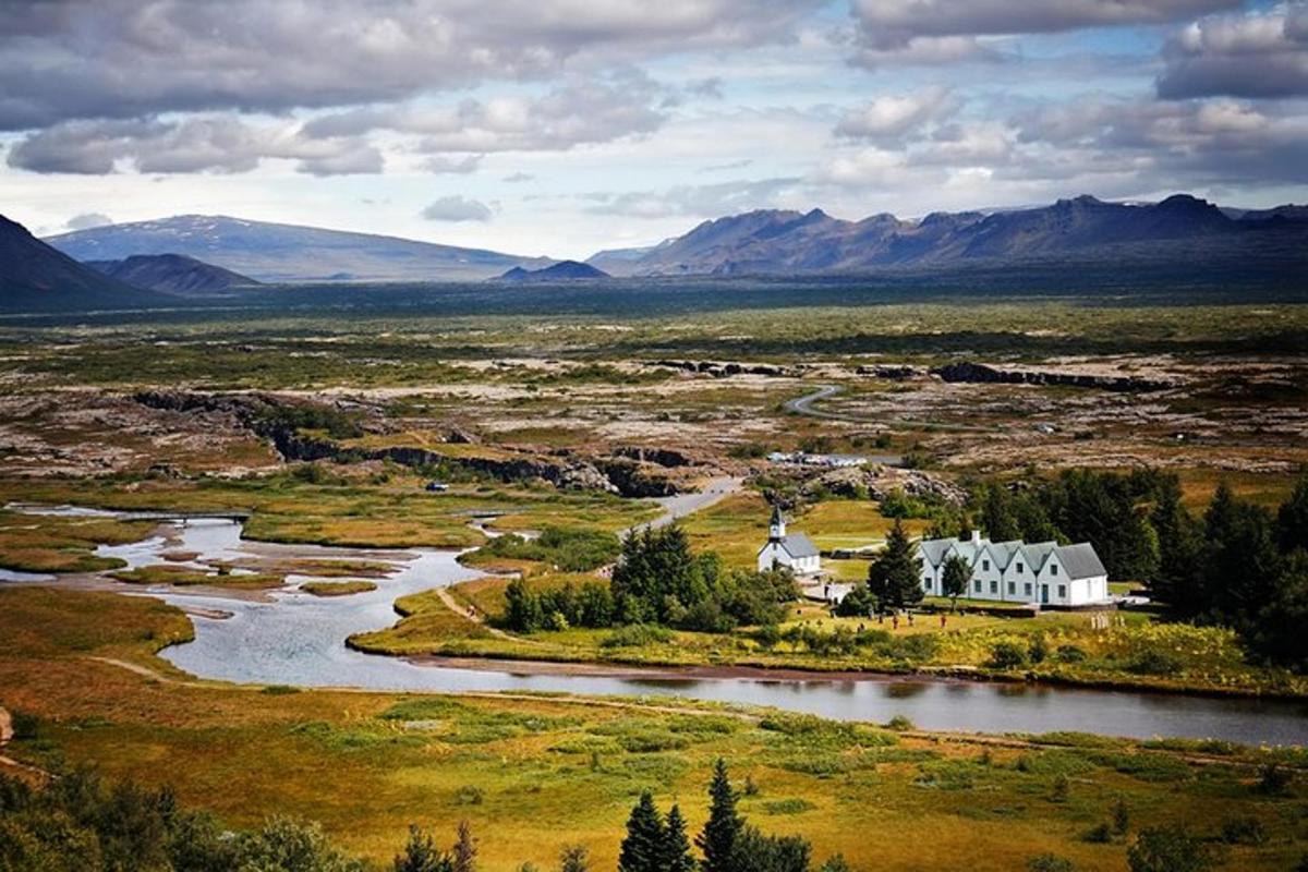 una casa en un campo con un río y montañas