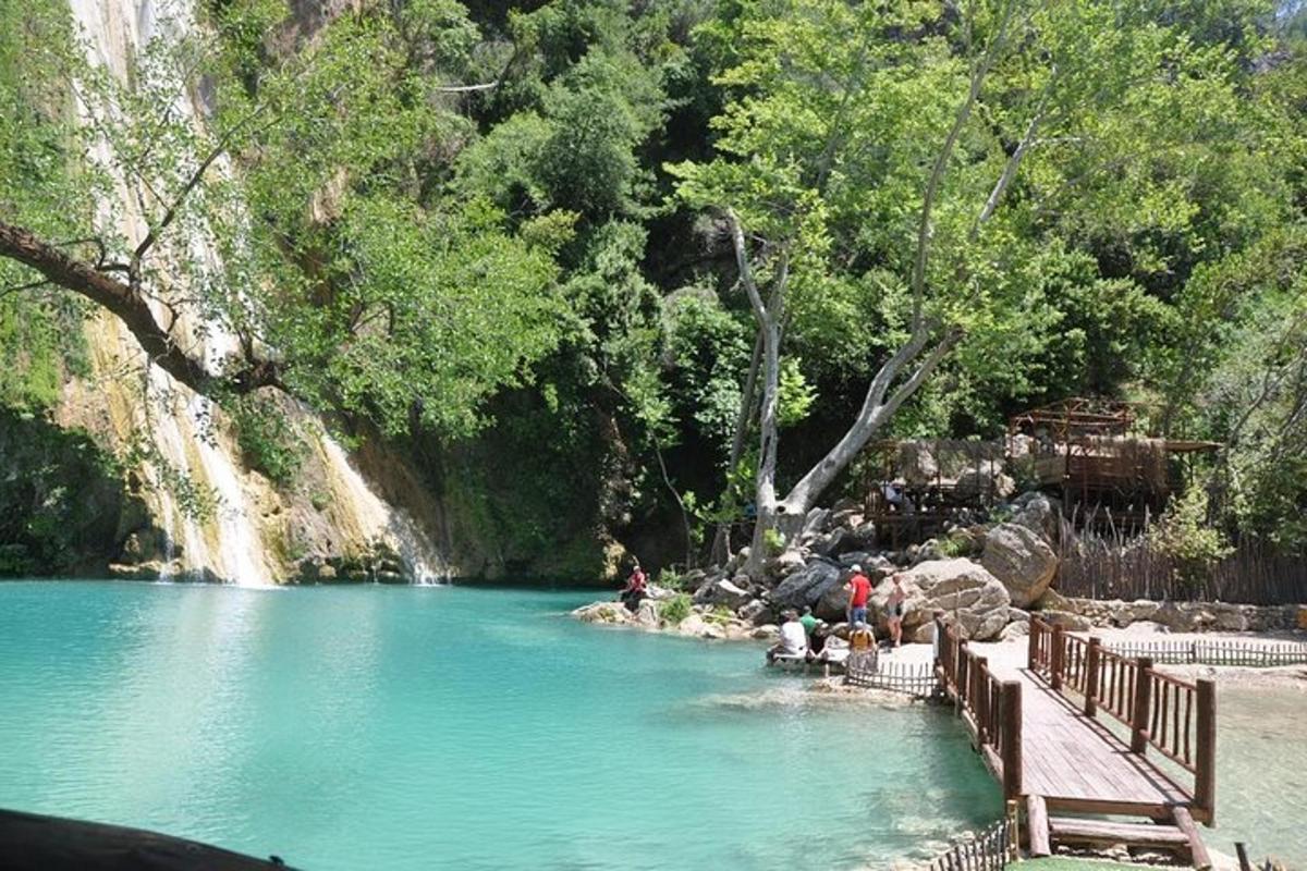 a pool of water with people sitting on a wooden bridge