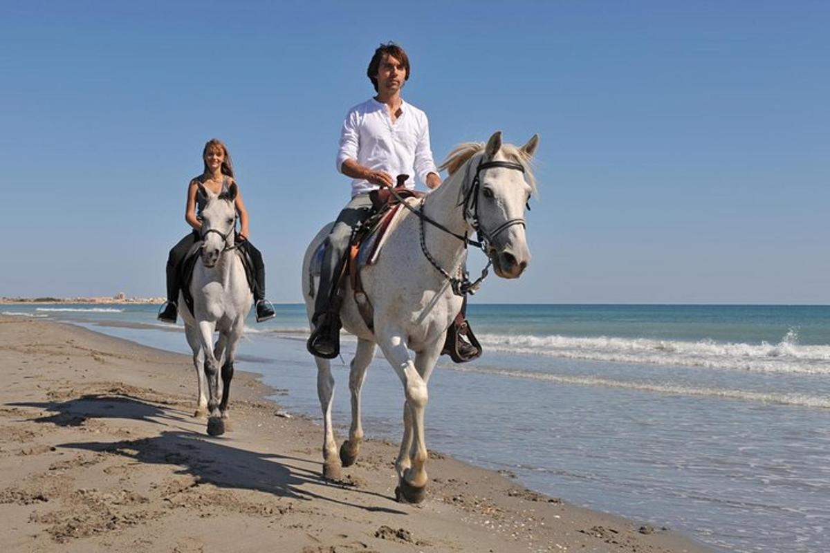 two people riding horses on the beach