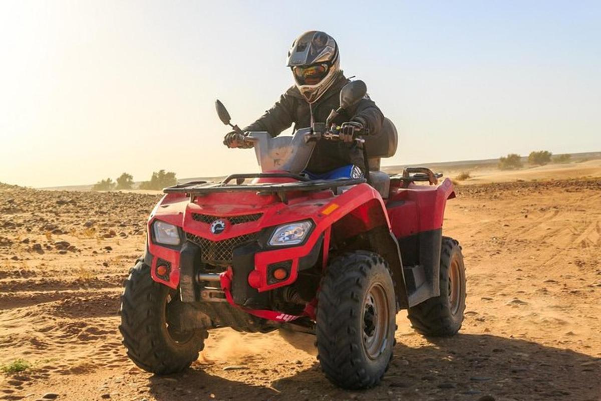 una persona che guida un quad rosso nel deserto