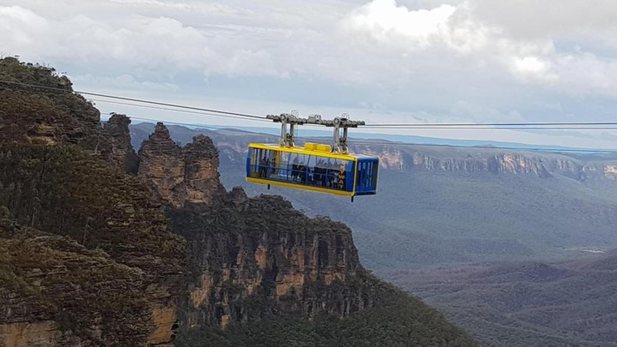 Un teleférico amarillo y azul volando sobre el Gran Cañón.