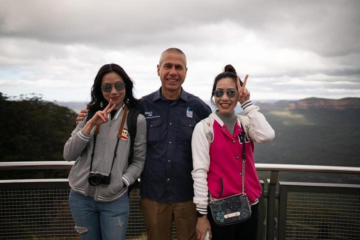 Un hombre y dos mujeres posando para una foto en la cima de una montaña.