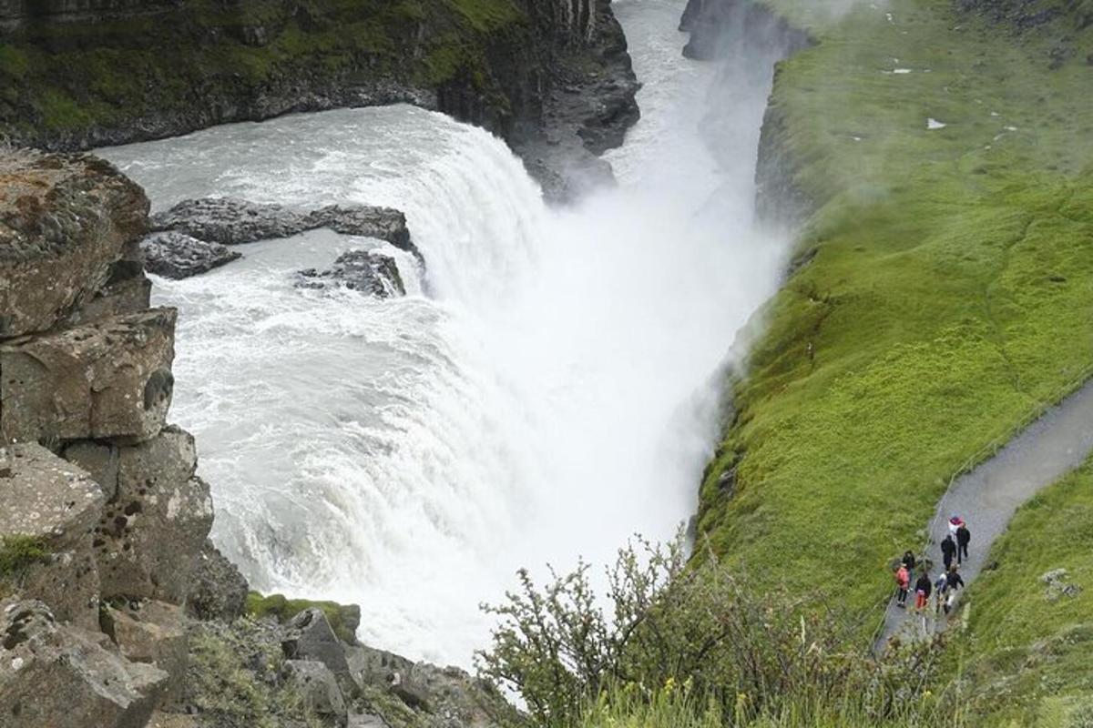 pessoas em pé em frente a uma cachoeira