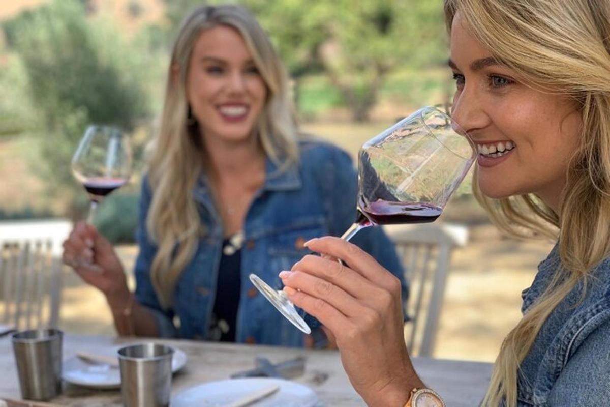 duas mulheres sentadas à mesa bebendo vinho