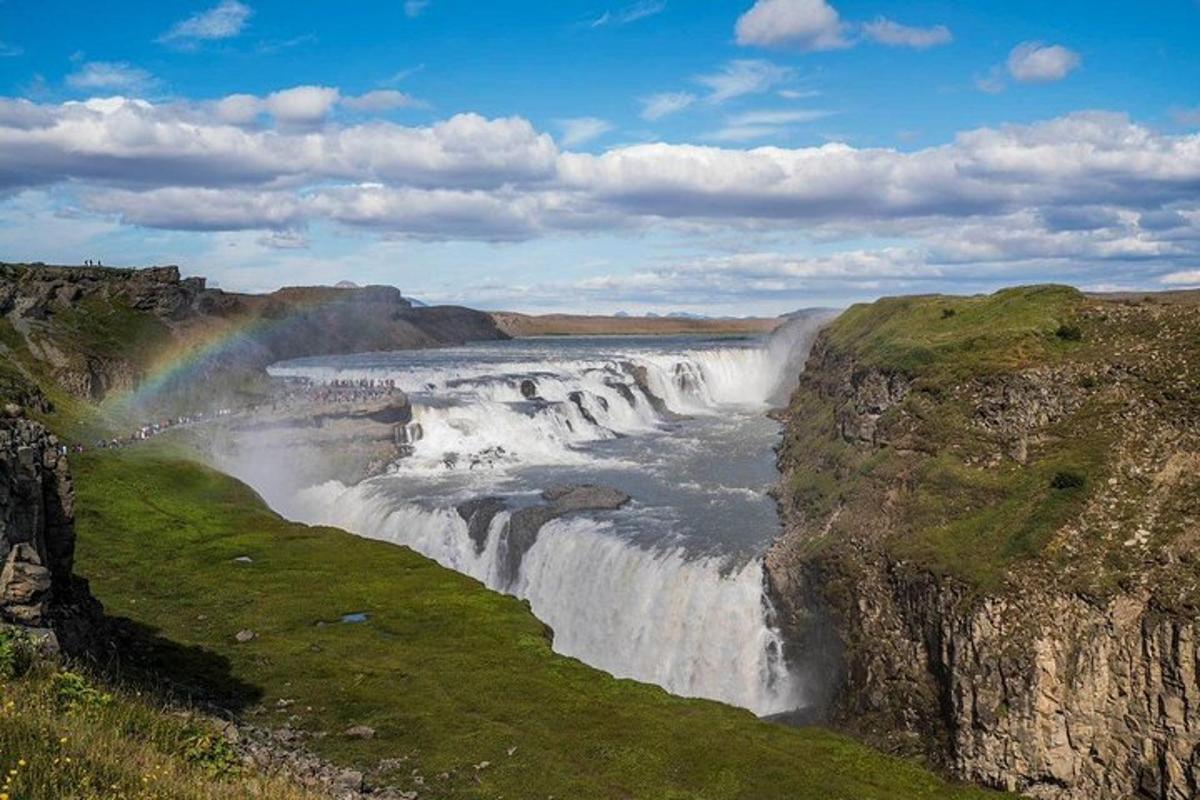 una cascata con un arcobaleno sul fianco di una montagna